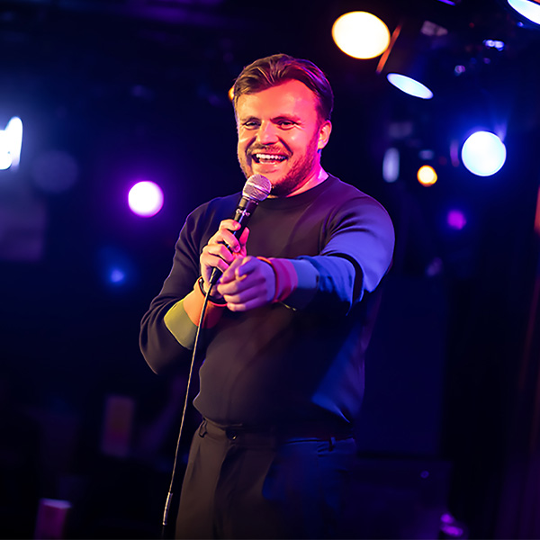 Lee Peart (a white man) talking into a microphone on stage.