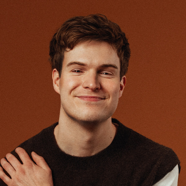 Thor Stenhaug, a white man with dark brown hair, wearing a black sweatshirt, on a brown background, smiling.